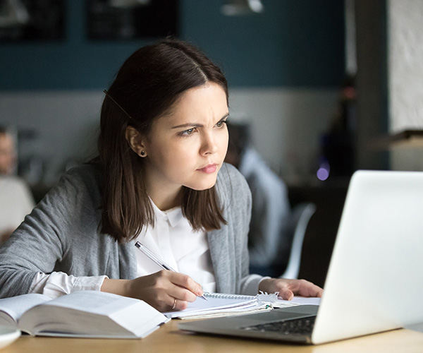 : Eine Frau schaut verwirrt auf ihren Laptop- sie nutzt Textformeln um ihren Texter besser zu strukturieren